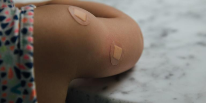 Child’s Arm with two band-aids after a vaccine (CC0 Charles Deluvio on Unsplash)