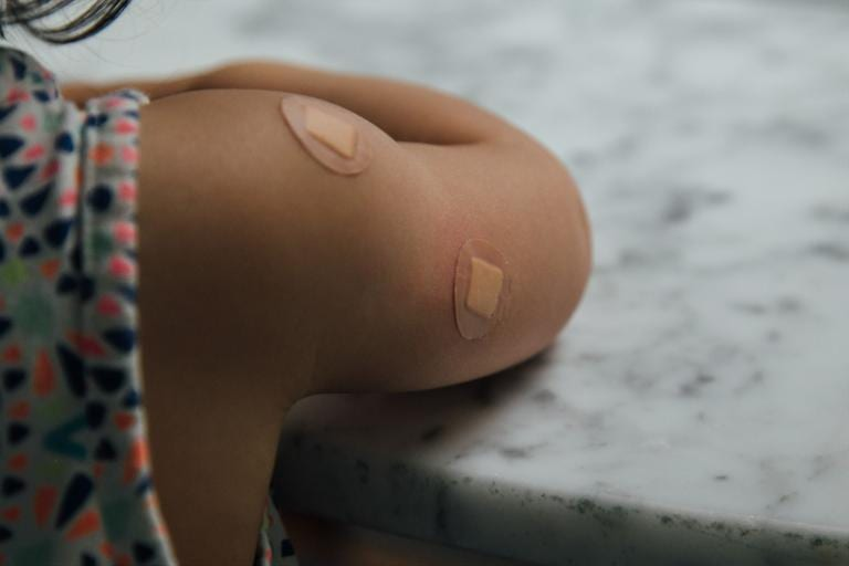 Child’s Arm with two band-aids after a vaccine (CC0 Charles Deluvio on Unsplash)